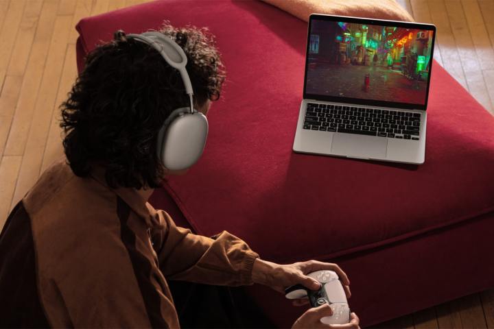 Apple MacBook Air M4: Prix, Date de sortie, Design, Performance & Caractéristiques 9 Une personne joue errant à l'aide d'un contrôleur PlayStation sur un MacBook Air argenté de 13 pouces.